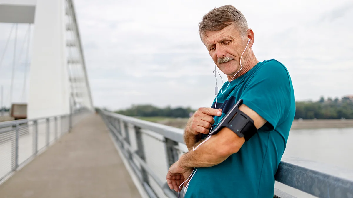 Older runners, one with a smartphone, tying shoelaces.